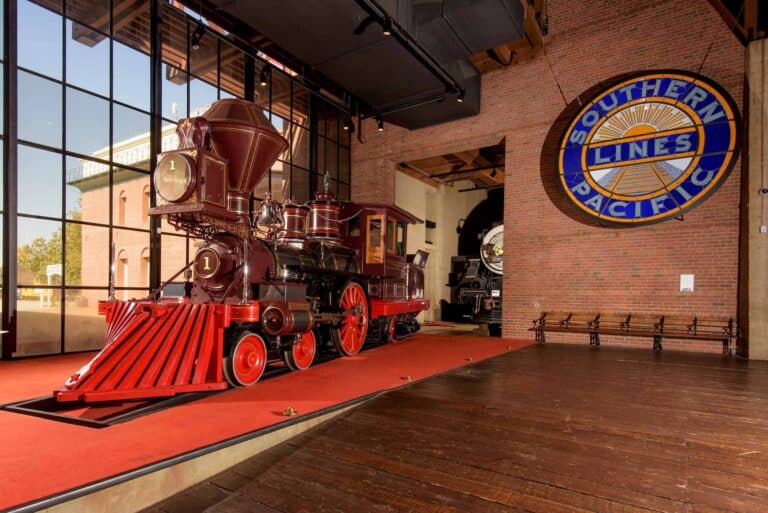 Vintage Southern Pacific locomotive inside a museum with brick walls and wooden floor.