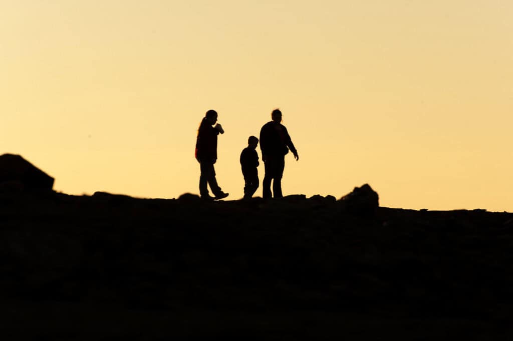 Silhouettes of three hikers during sunset at California park.
